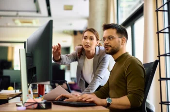 Profissionais analisando um projeto em computador durante trabalho colaborativo em escritório.